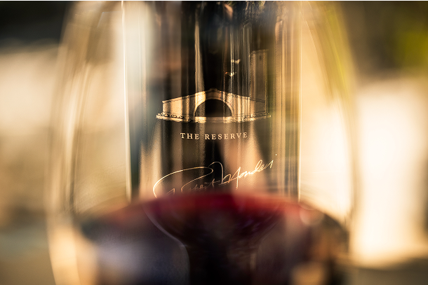 Glass of red wine with a bottle of Robert Mondavi Reserve behind it