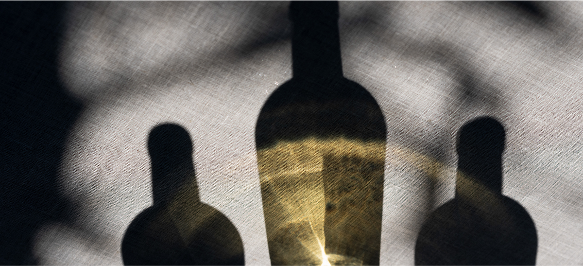 Two silhouettes of people with a bottle between them on a textured background