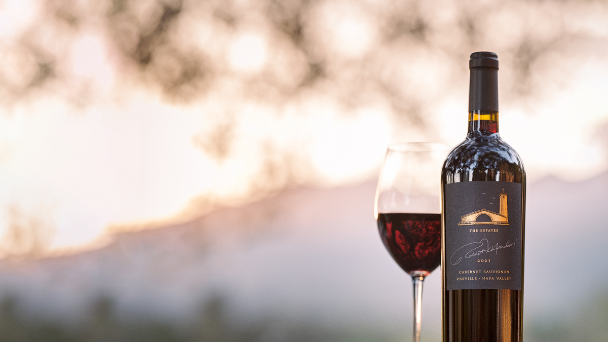 Bottle of 2021 Estate Cabernet Sauvignon Oakville outside with a glass of wine to the left 